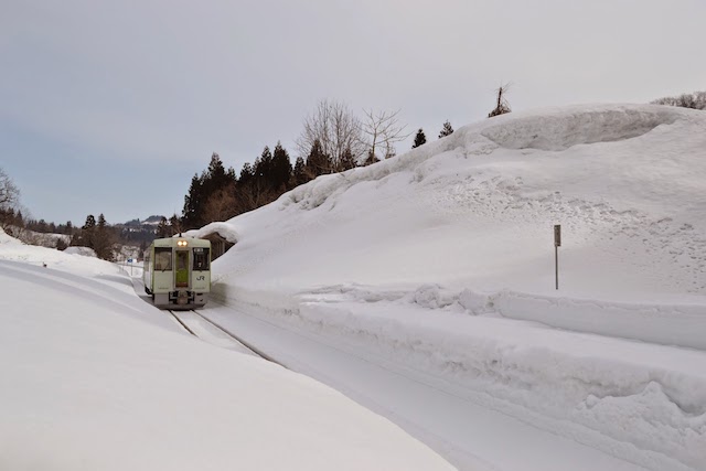 雪が積もる飯山線内ケ巻駅に到着するJR東日本キハ110系気動車(イメージ) ©Katsumi