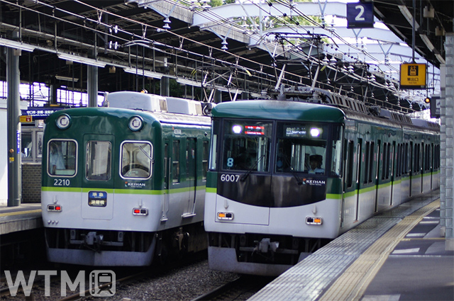 萱島駅に停車中の京阪2200系電車(左)と通過する6000系電車(Kazugram/写真AC)