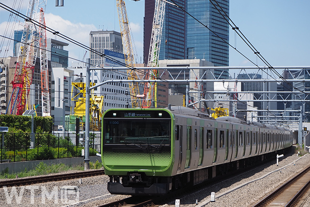 「高輪ゲートウェイシティ(仮称)」の開発工事が進む高輪ゲートウェイ駅付近を走行するJR東日本E235系電車(Katsumi/TOKYO STUDIO)